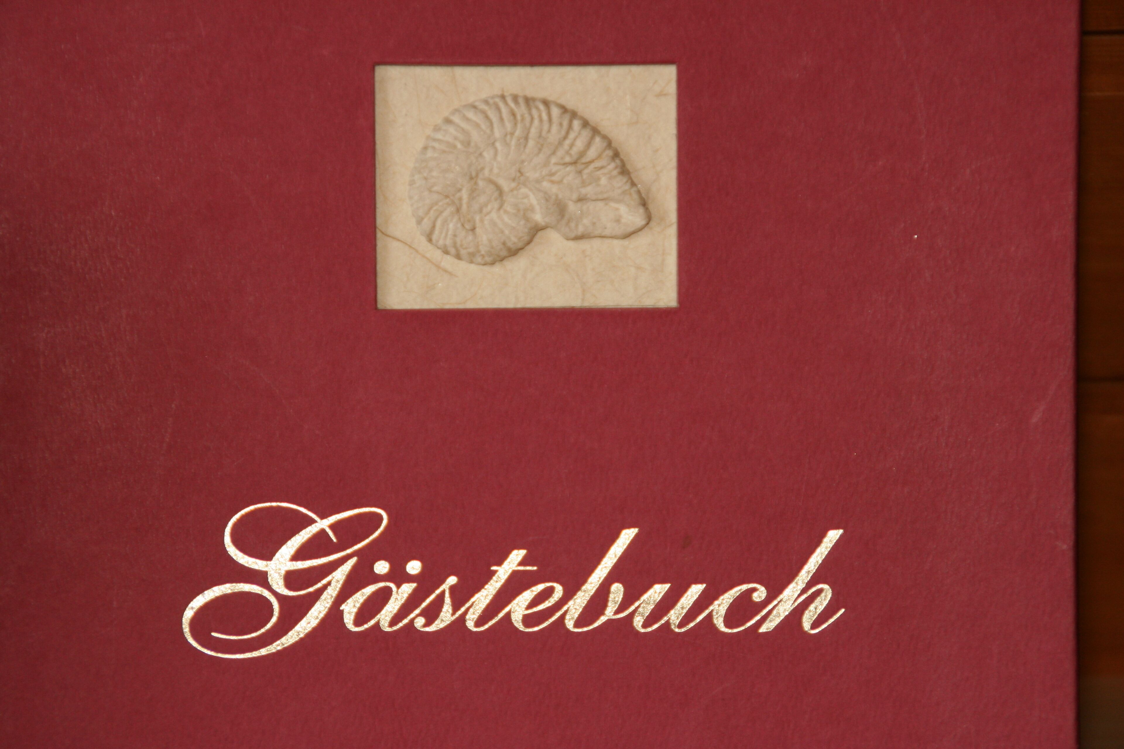 A red book with a fossil imprint and the text "Gästebuch" on the cover.