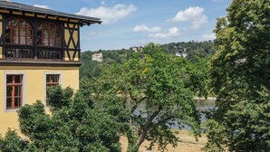 Ein gelbes Gebäude mit Balkon, umgeben von Bäumen und einem See.