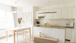 Eine moderne Küche mit weißen Schränken, einer Holz Arbeitsplatte und einer Mikrowelle. Es gibt einen Essbereich mit Tisch und Stühlen, und auf dem Tisch steht ein Blumenstrauß in einer Vase.
