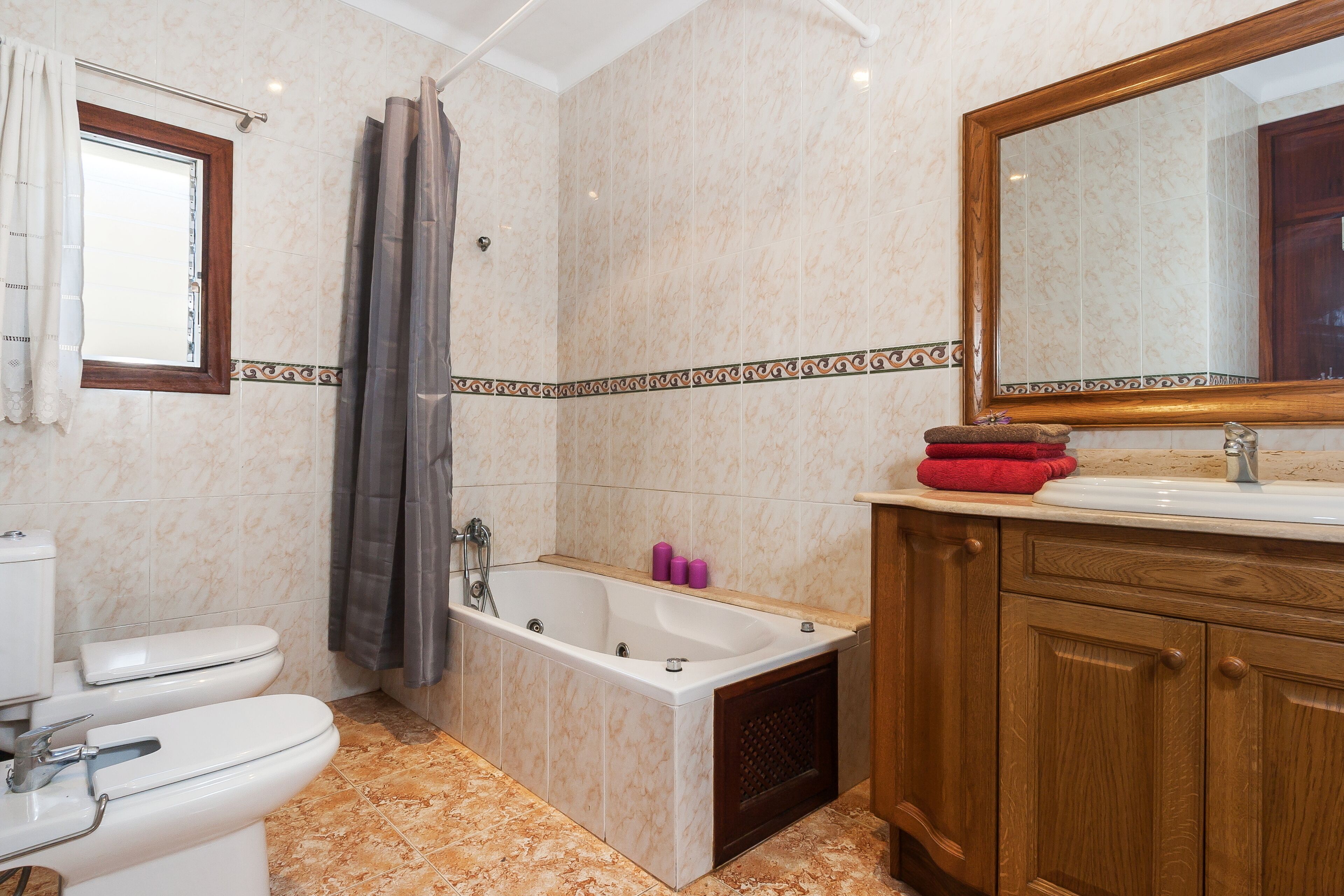 A bathroom with a toilet, bathtub, and wooden vanity with a mirror.