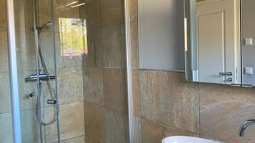 Un bagno con doccia vetrata, lavandino bianco e uno specchio grande.