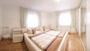 Une chambre à coucher avec un grand lit, deux tables de chevet, une chaise et une armoire.