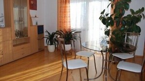 Un coin repas comprenant un buffet en bois, une table en verre et des chaises.