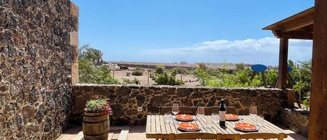 A stone wall, a wooden table with orange plates, and a view of a distant landscape.