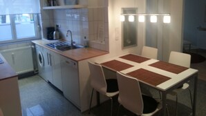 A compact kitchen with a sink, a washing machine, and a table with chairs.