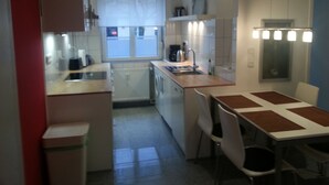 A compact kitchen with a central island, a dining table with chairs, and a window with blinds.