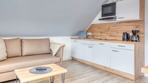 Een moderne keuken met witte kasten, een houten aanrechtblad en een ingebouwde magnetron.