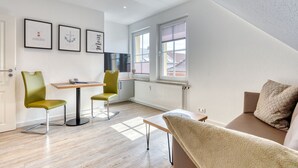 Een moderne woonkamer met een bank, een eettafel met stoelen, een televisie en beelde op de muur.