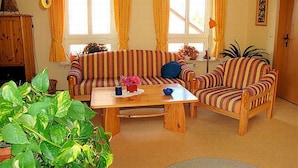 A cozy living room with striped sofas, a wooden coffee table, and a large window with curtains. - Apartment 1 Rosenträger - Apartments Rosenträger (Kappeln)