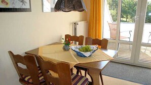 A dining area with a table set for four, surrounded by wooden chairs with striped cushions. - Apartment 1 Rosenträger - Apartments Rosenträger (Kappeln)