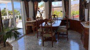 A dining area with a marble floor, wooden chairs, a table, and curtains.