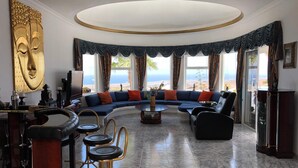 A spacious living room with a curved sofa, a coffee table, and a bar area with stools.