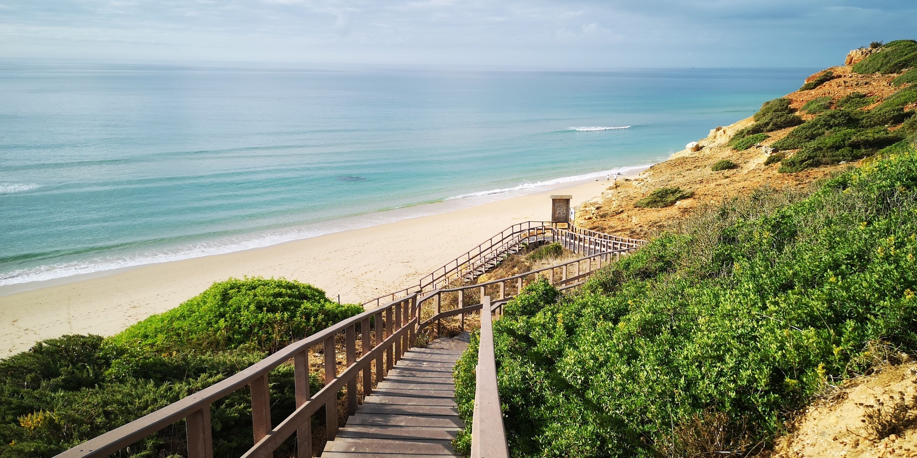 Una escalera que baja a una playa con vista al océano.