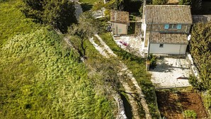 Vue aérienne d’une propriété rurale comprenant une maison, un jardin et un chemin de terre.