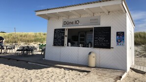 Ein kleines weißes Gebäude mit einem Schild, auf dem "Düne IQ" und "OSTSEEHOTEL DIERHAGEN" steht.