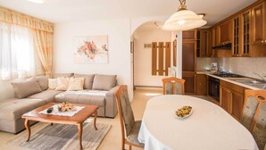 A living room with a sofa, a dining table, and a kitchen area with wooden cabinets and a stove. - A luxurious house in a quiet village near the sea (Labin)