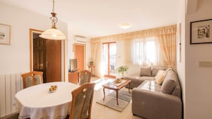 A living room with a sofa, a dining table with chairs, a coffee table, and a ceiling light fixture. - A luxurious house in a quiet village near the sea (Labin)