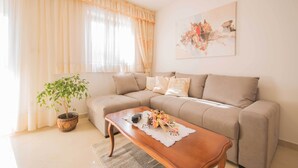 A living room with a beige sofa, a wooden coffee table, a potted plant, and a painting on the wall. - A luxurious house in a quiet village near the sea (Labin)
