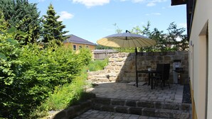 A stone patio with a table and chairs, an umbrella, and a stone wall. - Apartment with terrace, in the heart of the Elbe Sandstone Mountains, ideal for hiking (Bad Schandau)