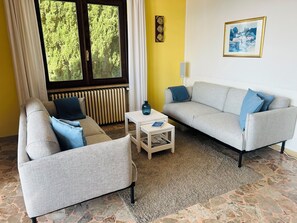 A living room with two grey sofas, a small white table, and a radiator.