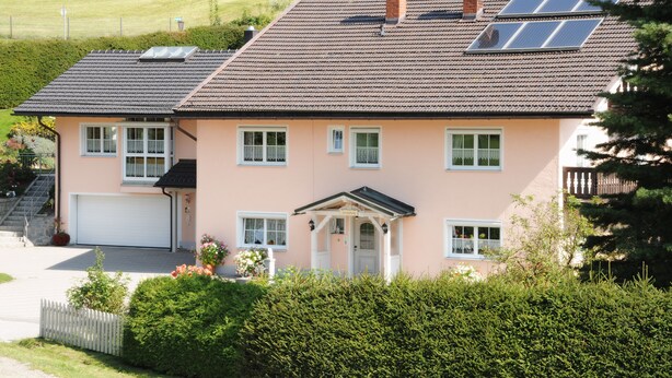 A two-story house with a garage, solar panels, and a well-maintained garden.