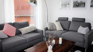 A modern living room with grey sofas, a wooden coffee table, and a floor lamp. - Dünenperle-Borkum, 5 stars, 3 bedrooms, 2 bathrooms, roof terrace (Borkum)