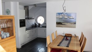 A modern kitchen with white cabinets, a black oven, and a round window. - Dünenperle-Borkum, 5 stars, 3 bedrooms, 2 bathrooms, roof terrace (Borkum)