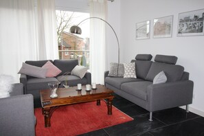 A modern living room with two grey sofas, a wooden coffee table, and a red rug. - Dünenperle-Borkum, 5 stars, 3 bedrooms, 2 bathrooms, roof terrace (Borkum)