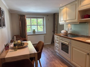 A kitchen with a dining table, chairs, a stove, and cabinets.