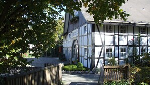 Un bâtiment traditionnel à colombages, avec un chemin de pierre menant à un pont en bois.