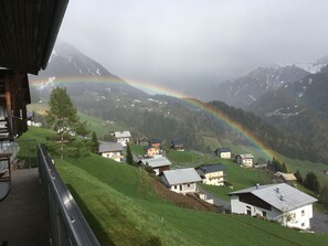 A view of a mountain village with houses and a rainbow.