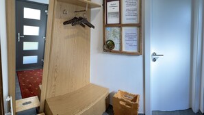 A hallway with a wooden door, a small wooden bench, and a red carpet. - Vacation apartment**** with sauna, herbal steam bath, solarium and fitness room (Fontanella)