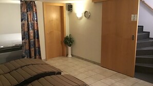 A hotel room with a bed, a potted plant, a clock, and a staircase. - Vacation apartment**** with sauna, herbal steam bath, solarium and fitness room (Fontanella)