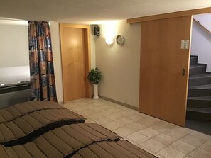 Una habitación de hotel con cama, una planta en maceta, un reloj y una escalera.