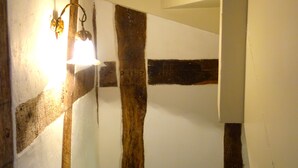 Une petite salle de bain avec une poutre en bois, un lavabo blanc et une tasse posée sur le comptoir.