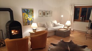 A living room with a fireplace, sofas, a rug, and a painting on the wall. - Vacation home in a fantastic location in Upper Bavaria (Oberhausen)