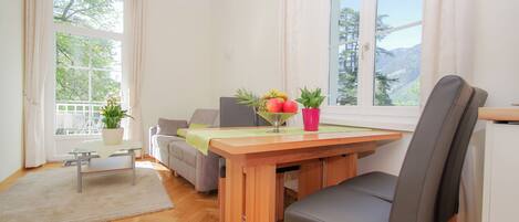 A dining area with a wooden table, chairs, and a view of mountains through large windows.