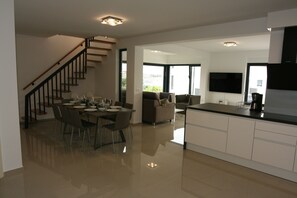 Una cocina moderna con comedor, una escalera y una sala de estar con sofá.