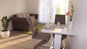 A modern living room with a sofa, a dining table with chairs, a potted plant, and a vase with a flower. - Lake Constance, Friedrichshafen, central location, 2 people, Lake Constance center (Friedrichshafen)
