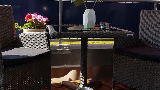 An outdoor patio with wicker furniture, a table, and an orange umbrella. - Lake Constance, Friedrichshafen, central location, 2 people, Lake Constance center (Friedrichshafen)