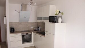 A compact kitchen with white cabinets, a built-in microwave, a coffee maker, and a toaster. - Lake Constance, Friedrichshafen, central location, 2 people, Lake Constance center (Friedrichshafen)