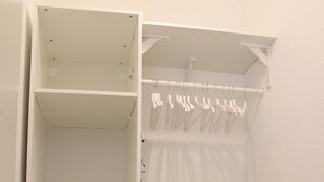 A white walk-in closet with open shelves, a hanging rod, and a sliding door. - Lake Constance, Friedrichshafen, central location, 2 people, Lake Constance center (Friedrichshafen)