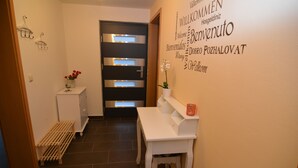 A hallway with a modern door, a white console table, and a wall with multilingual welcome signs. - Franconian idyll at Bamberg (Stegaurach)