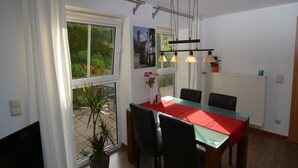 A dining area with a glass table, red tablecloth, black chairs, and a hanging light fixture. - Franconian idyll at Bamberg (Stegaurach)