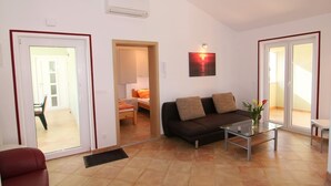 Ein Wohnzimmer mit einer Couch, einem Glastisch und einer Tür zu einem anderen Raum.