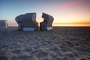 Sedie da spiaggia con i numeri 59 e 57 su una spiaggia sabbiosa al tramonto.