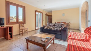 A living room with a sofa, a coffee table, a TV, and a bookshelf. - Cosy Holiday Apartment with Wi-Fi, Air Conditioning and Terrace (Binissalem)