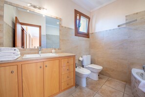 A bathroom with a wooden vanity, a large mirror, a toilet, and a bathtub.