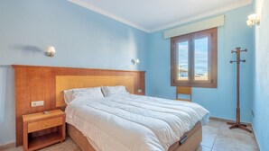 A bedroom with a wooden headboard, a single bed, a nightstand, a lamp, and a window with a view. - Cosy Holiday Apartment with Wi-Fi, Air Conditioning and Terrace (Binissalem)