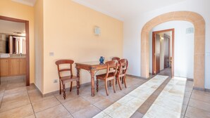 A dining area with a wooden table and chairs, a tiled floor, and a hallway with an archway. - Cosy Holiday Apartment with Wi-Fi, Air Conditioning and Terrace (Binissalem)
